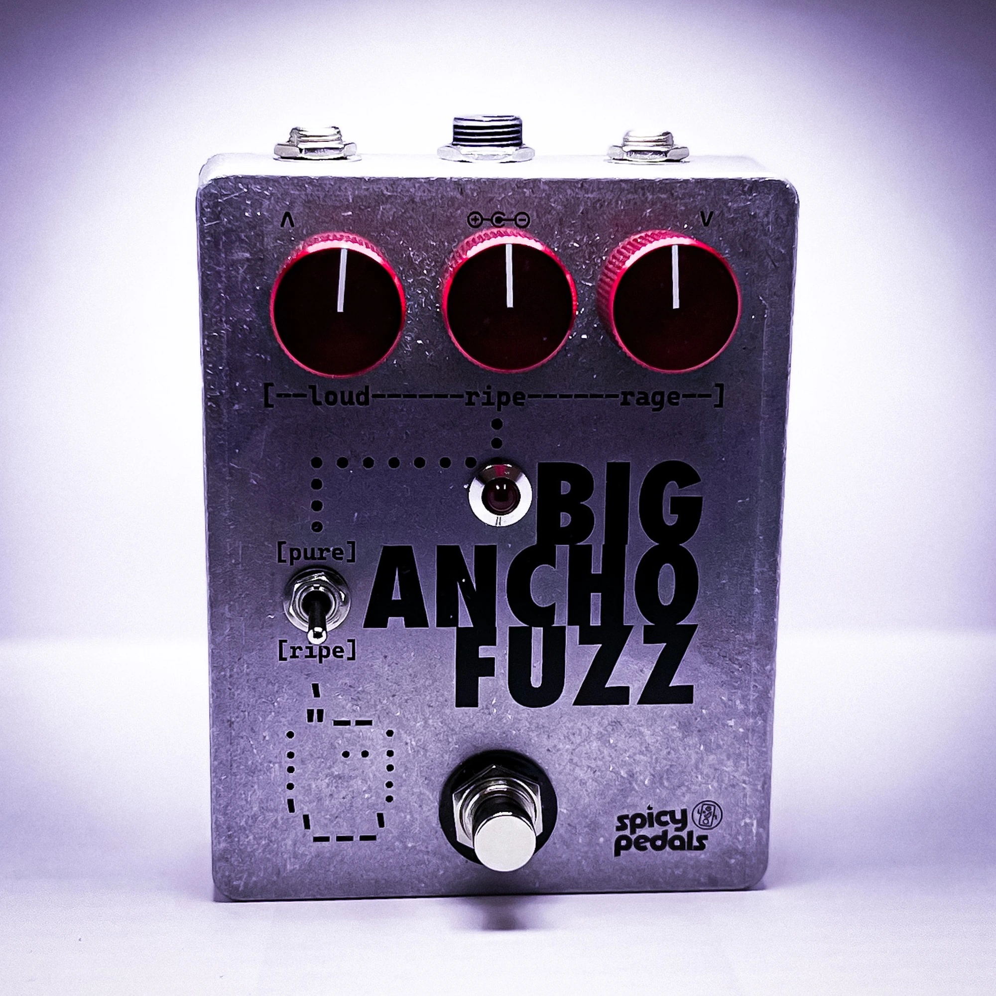 Big Ancho Fuzz lit by a purple key light, seen from three quarters, the aluminium enclosure and dark red knobs against a violet glow.