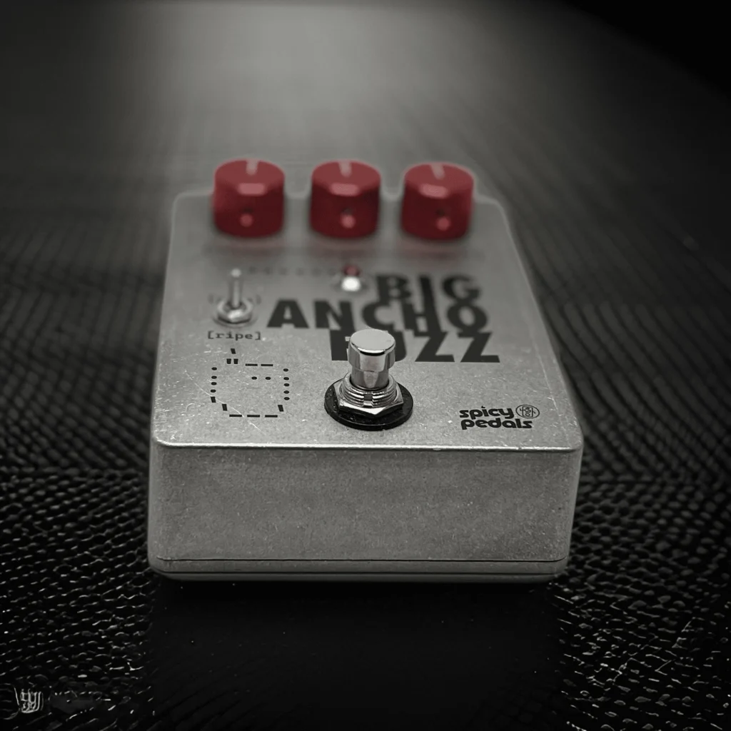 Big Ancho Fuzz lying on a dark textured surface, low angle, showing the depth of the aluminium enclosure and the side of the footswitch.