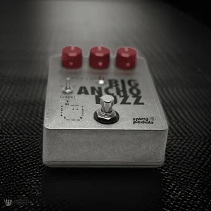 Big Ancho Fuzz lying on a dark textured surface, low angle, showing the depth of the aluminium enclosure and the side of the footswitch.
