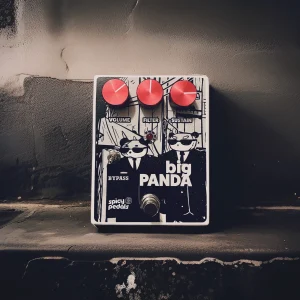 Big Panda standing against a weathered grey plaster wall, seen from three quarters, the panda artwork and the red knobs catching the light.
