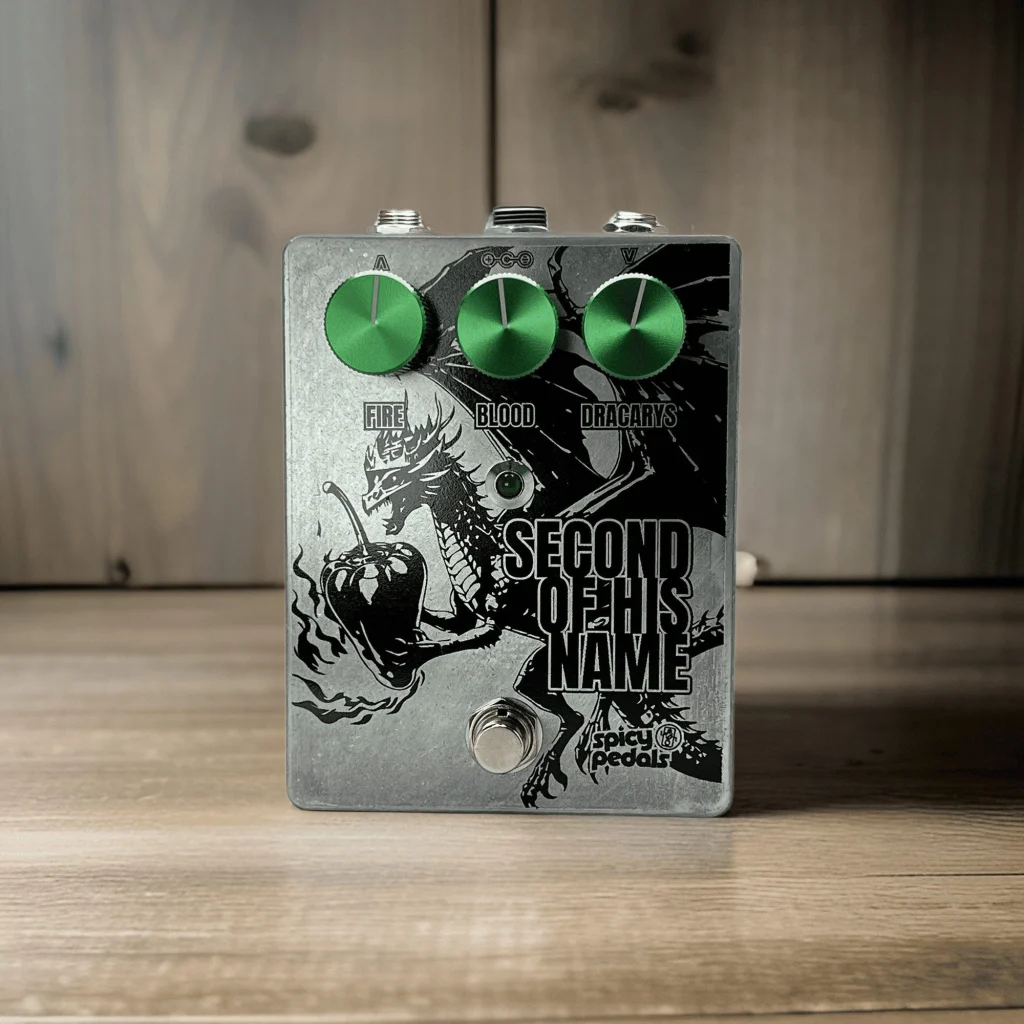 Second Of His Name standing on pale wood against a pale wooden wall, seen from three quarters, the aluminium enclosure and green knobs in even light.